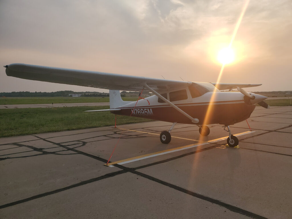 Small aircraft parked on the runway at sunset, representing pilot-focused FAA exams and aviation care at Kansas Aviation Medicine.